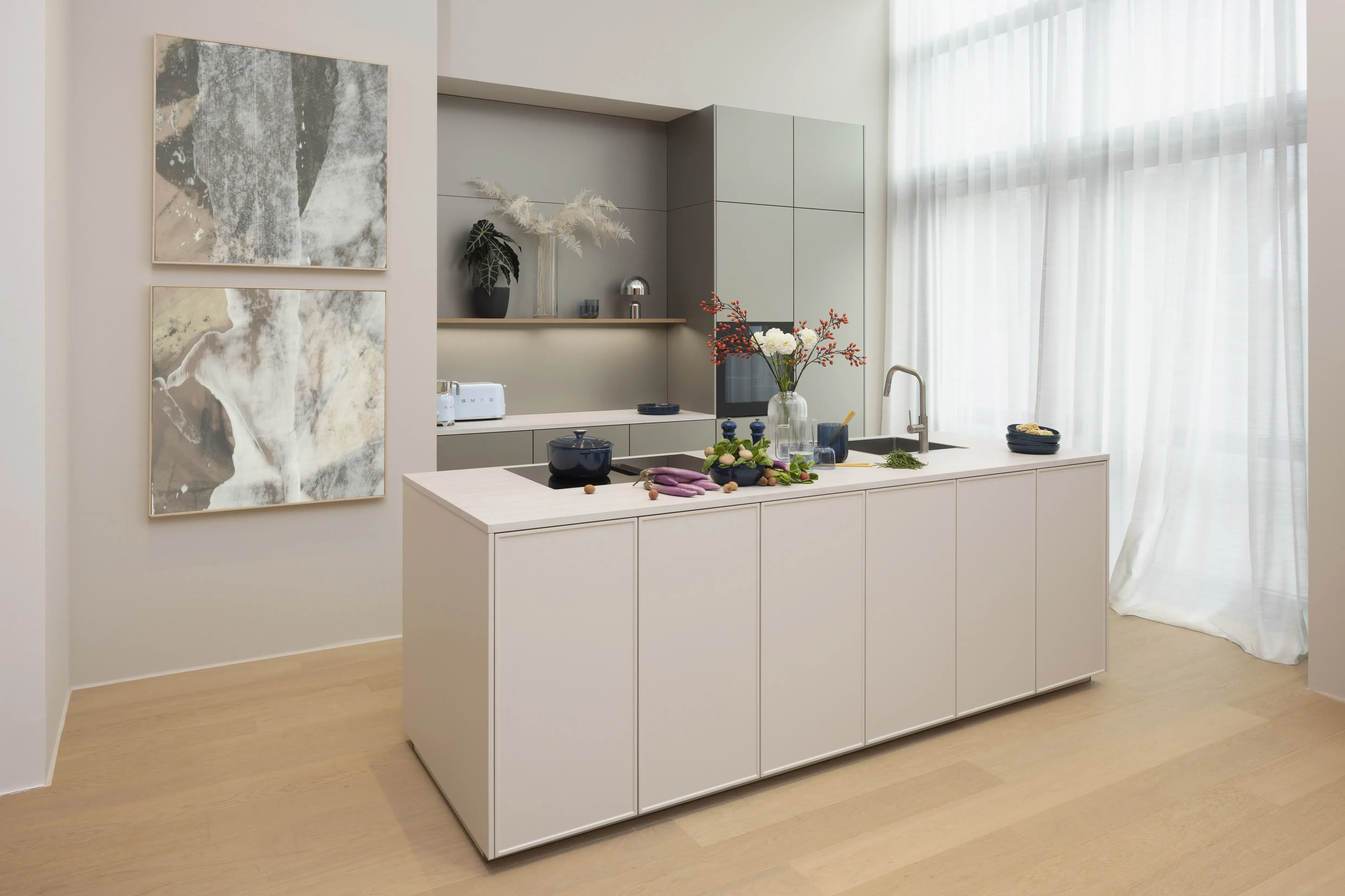 Moderne, helle Küche mit Kochinsel, Blumen und großen Fenstern, Wandbilder links